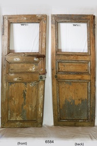 Wooden door with top frame where window was inserted. Remnants of light coloured paint on the surface.