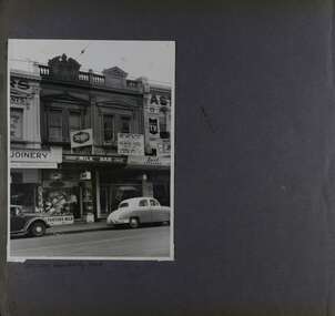 1 photo on page - view of old-style double storey shops with old cars parked out the front.