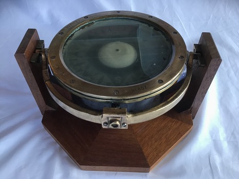 Side view of compass from the 'SS Time' mounted on a wooden frame for display.