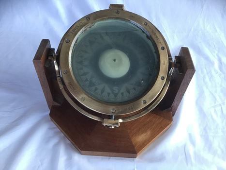 Top view of compass from the 'SS Time' mounted on a wooden frame for display.