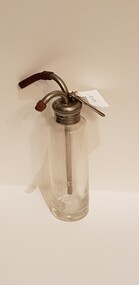A clear glass bottle with etched liquid measurements on the side, and a metal lid with tubes ending with rubber stoppers.