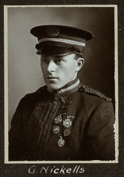 Black and white photograph of a man in a uniform and cap with his name written underneath on the mount