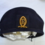 Front view of navy blue wool beret with a school crest embroidered in yellow gold thread attached to the centre front.