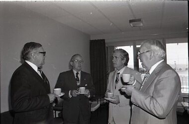 Four men holds cups and saucers at an office at Brighton