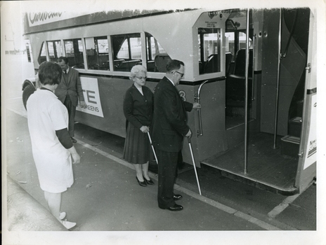 Two people board a bus using their white canes to guide them