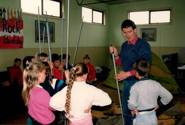 A teacher explaining the rules of a game to six children. 