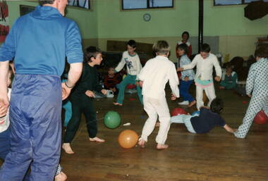 Six boys dressed in pyjamas playing indoor soccer with balloons.