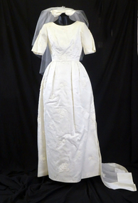 1963 Wedding dress of cream satin; floor length, short sleeves, round neckline (front)