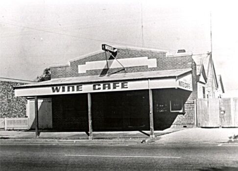 Wine Cafe building at the front of block. Additional buildings at the rear. Corrugated iron gate to the right.