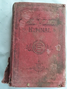 The red cloth badly damaged hymnal has black and gold faded lettering of title and symbol of E surrounded by a circle on the front cover.