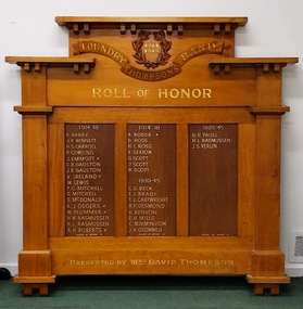 Photograph of the front of light varnished timber honor board depicting names of bandsmen who served in world war one and two.