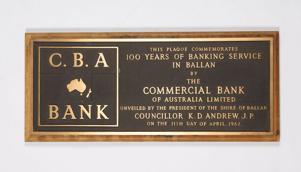 A large, heavy brass commemorative plaque mounted on a timber backing.