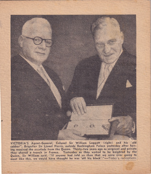 Two men wearing suits standing side-by-side both holding book between them 