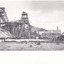 a black and white photograph of an early 1900s style mine, with buildings  and chimneys in the background.