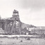 a black and white photograph of an early 1900s style mine, with buildings  and chimneys in the background.