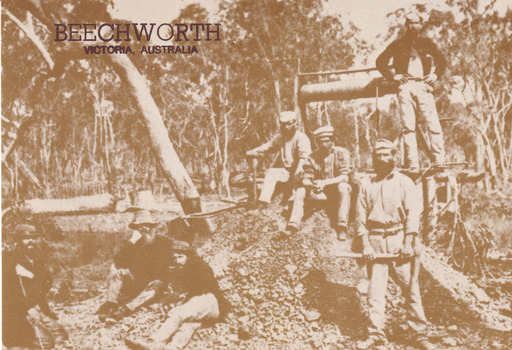 A sepia toned postcard depicting five men sitting and two men standing next to a mine shaft located in Beechworth. In the background is dense bush.