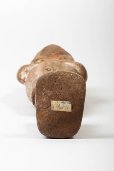 Closeup of the bottom of the Ushabti, under the foot. A paper identification tag is visible 