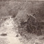 River flowing through scrub towards a metal wheel; part of a mine set up.