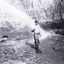Photograph of a man standing in a wet mining excavation pit holding a shovel