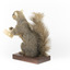 Squirrel standing on a wooden platform and holding a small pinecone with a paper tag tied to one arm.