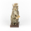 Squirrel standing on a wooden platform and holding a small pinecone with a paper tag tied to one arm.