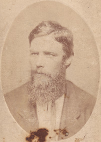 A portrait of light skin tone man, with a long bushy beard, and formally dressed. He is looking off to his right side. 
