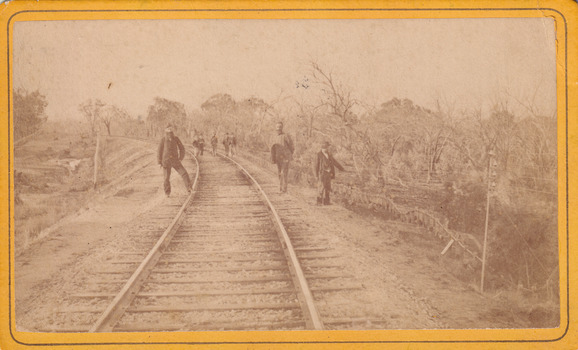 Eight men standing along railway line near Glenrowan