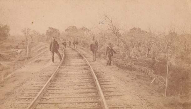 Eight men standing along railway line near Glenrowan