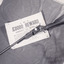 A black and white photograph of a rifle sitting across a poster offering an £8000 reward for robbery and murder. The two objects are resting on a dark material which sits on a shaggy surface.