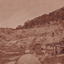 Image taken at El Dorado Cocks Pioneer Gold and Tin Sluicing Company looking east up open cut from barge site. Image depicts unevenly cut rock with a small timber structure on the right of the image