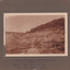 Image with wide frame taken at El Dorado Cocks Pioneer Gold and Tin Sluicing Company looking east up open cut from barge site. Image depicts unevenly cut rock with a small timber structure on the right of the image