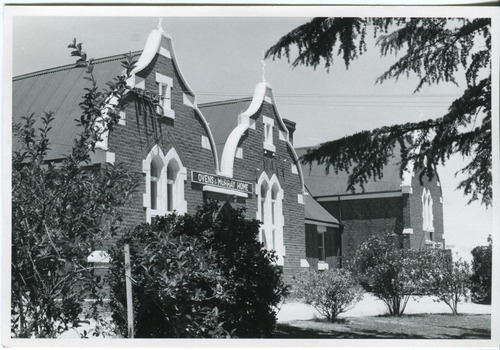 Group of buildings close together - gardens in front. On one building is a sign over the door: "Ovens & Murray Home"