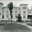 View of Mayday Hills hospital. Large building with lawn in front with fountain and some trees.