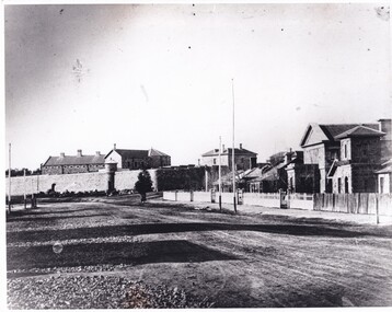 A black and white photograph of Ford street, Beechworth. In the background is the old Gaol with the Telegraphs Office, Gold Wardens and Courthouse Office on the right.