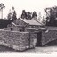 Black and white image of a stone building with trees in the background.