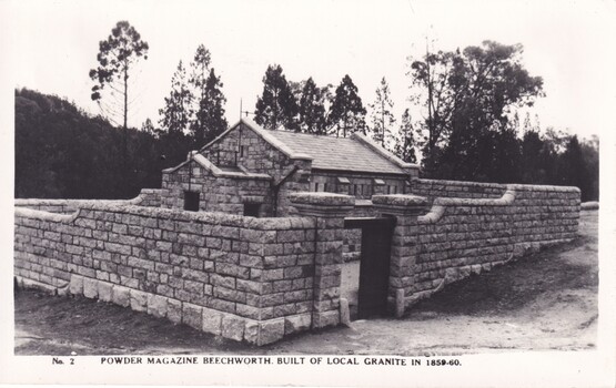 Black and white image of a stone building with trees in the background.