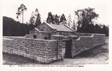 Black and white image of a stone building with trees in the background.
