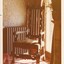 A photograph of a corner of a room featuring a vintage high-back arm chair next to a window.
