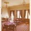 A photograph of a vintage  room with two poker tables, a lounge and french windows along one wall.