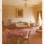 A photograph of a vintage room with poker tables, a lounge and a gilded painting hanging above it.