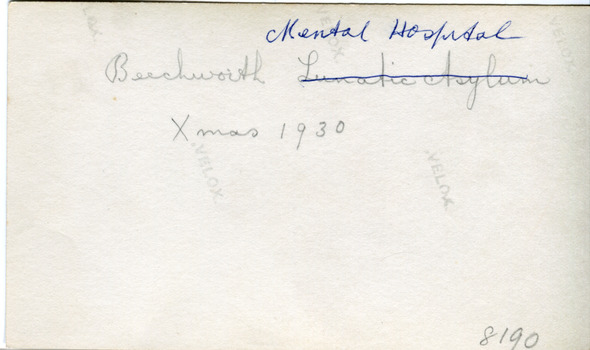 The reverse side of the photograph of the facade of MayDay Hills Mental Hospital with four 'Velox' watermarks. Inscribed in pencil is "Beechworth Lunatic Asylum Xmas 1930" with the 'Lunatic Asylum' crossed through with blue ink and written above is 'Mental Hospital'. In the bottom right is the collection item identifier number 8190
