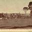 A sepia toned image of a landscape with trees, farmland, and a wooden fence in the foreground, and the May Day Hills Mental Hospital building in the background, partly obscured by trees. A boarder on bottom edge with text saying "Beautiful Beechworth (Vic.) 1800 ft. above Sea Level - General View of Asylum for Insane" with "Copyright. F. Foxcroft Photo" underneath