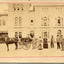 A child sitting in a horse drawn carriage surrounded by eight people in front of the Beechworth Mental Asylum's administration building 
