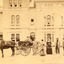 A child sitting in a horse drawn carriage surrounded by eight people in front of the Beechworth Mental Asylum's administration building 