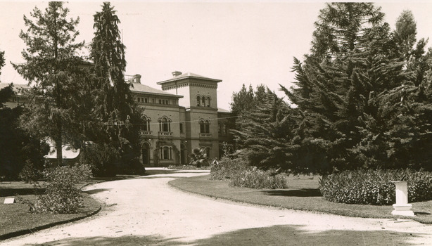 A sand pathway featuring manicured gardens on either side leading towards the Beechworth Mental Asylum administration building