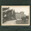 A pathway featuring manicured gardens on either side leading to the Beechworth Mental Asylum administration building. There are four males, three are sitting on the grass while one stands on one leg just behind them.