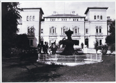 View of the Beechworth Lunatic Mental administration building with fountain in foreground. Three men and a small boy to the left of the fountain.