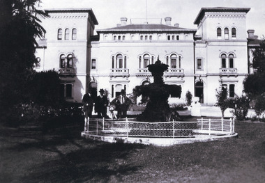 View of the Beechworth Mental Asylum administration building with fountain in foreground. Three men and a small boy to the left of the fountain.