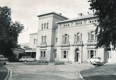 Rectangular black and white photograph of Beechworth Mental Hospital  (Mayday Hills)  facing towards the left hand side of the administrative building with three cars parked in driveway turning circle in the foreground.