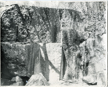 Rock face of a quarry, rock in the centre of the image has been marked at intervals in a vertical line. 